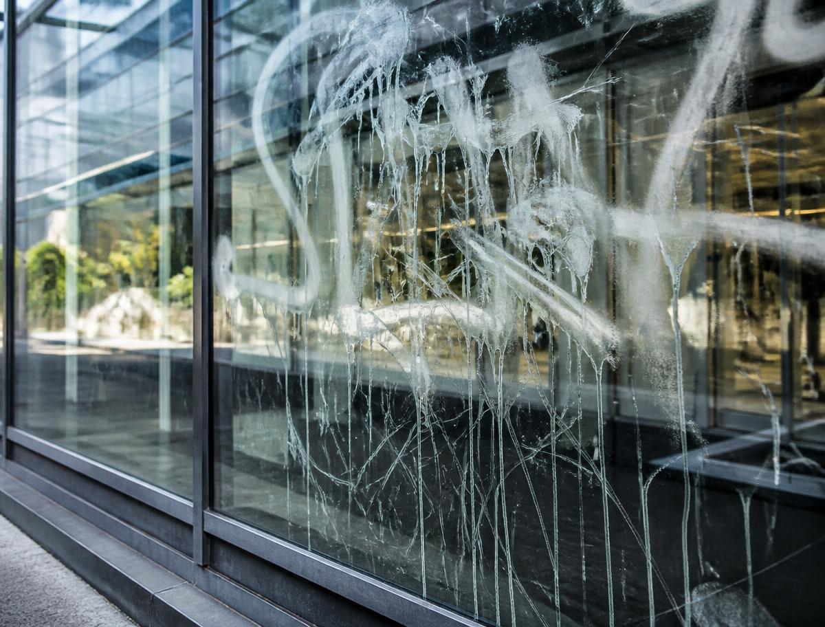 Storefront glass damaged by graffiti and scratches — the problem anti-graffiti film prevents