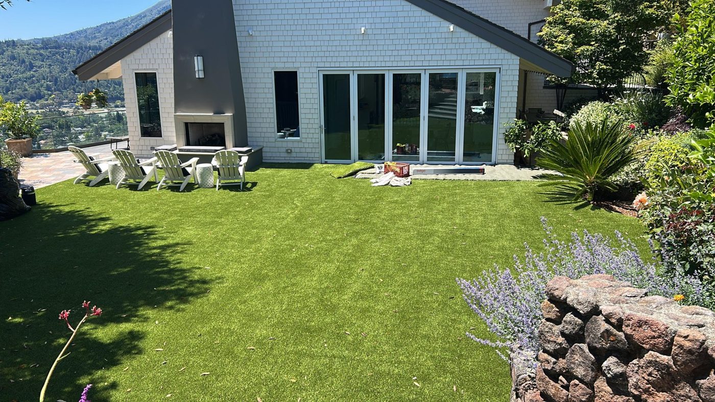Residential backyard with artificial turf and treated rear windows