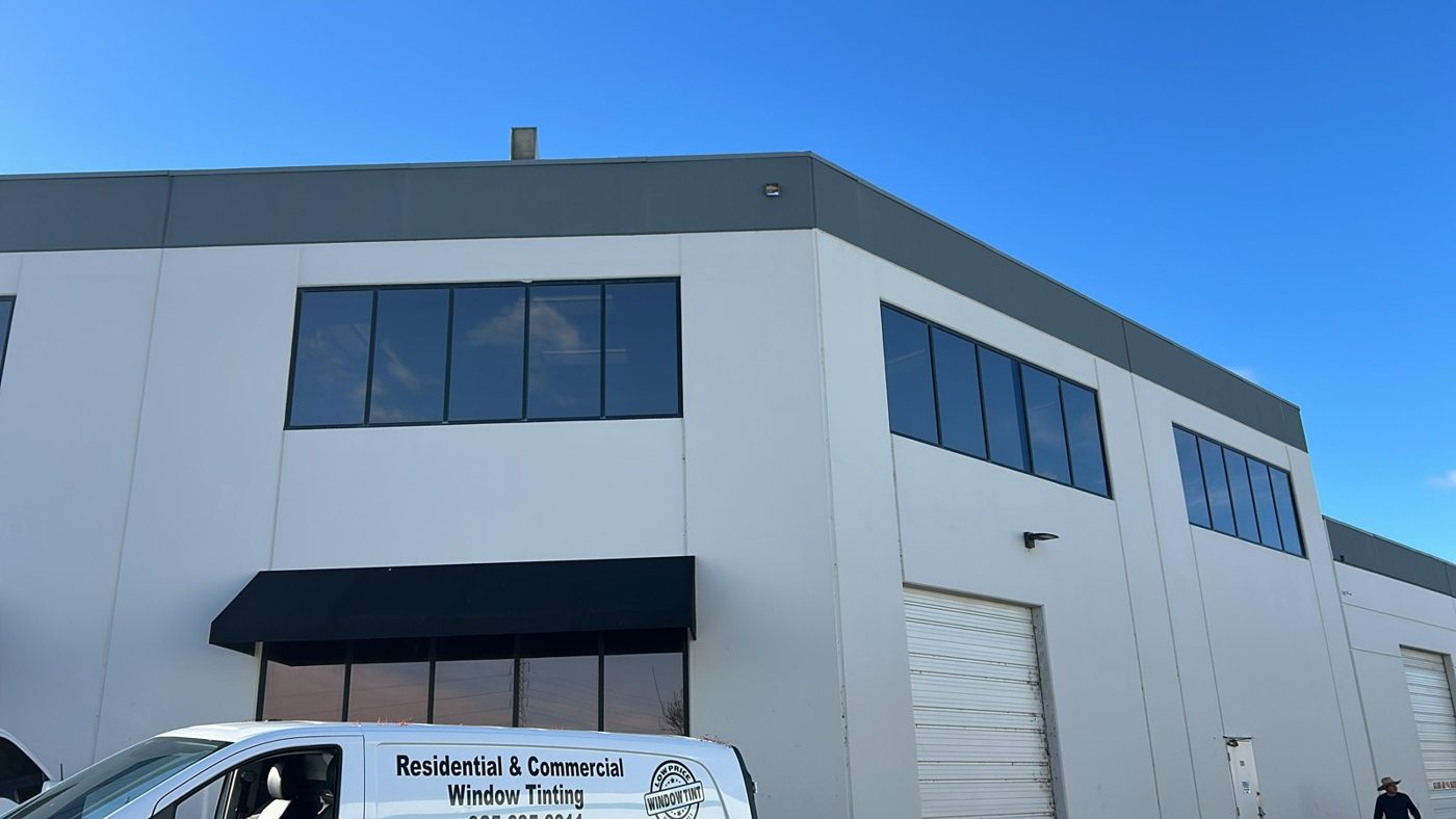 Two-story warehouse office building with dark window film on all exterior glass